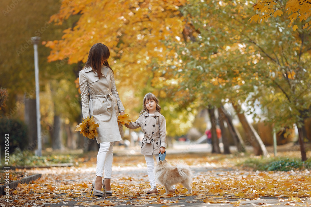Fototapeta premium Fashionable mother with daughter. Family in a autumn park. Family with a dog.