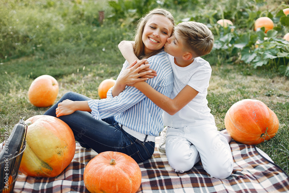 Fototapeta premium Family in a garden. People with pumpkins. Woman in a blue shirt