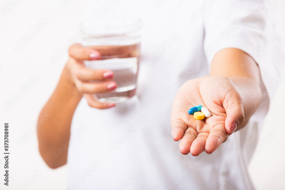 Closeup young Asian woman hold pill drugs in hand ready take medicines with a glass of water, studio shot isolated on white background, Healthcare and medical pharmacy concept Closeup young Asian woman hold pill drugs in hand ready take medicines with a glass of water, studio shot isolated on white background, Healthcare and medical pharmacy concept