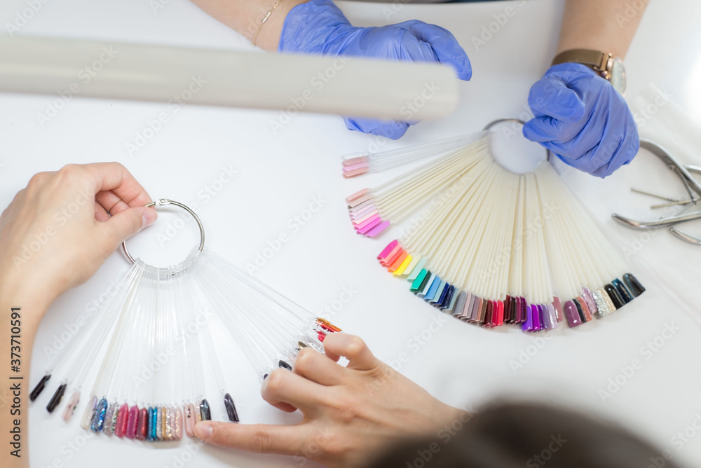 Choice of color of nails. a young girl of twenty-seven years old chooses a color for nails in a beauty salon. beauty and health of nails. Color and painting of manicure Choice of color of nails. a young girl of twenty-seven years old chooses a color for nails in a beauty salon. beauty and health of nails. Color and painting of manicure