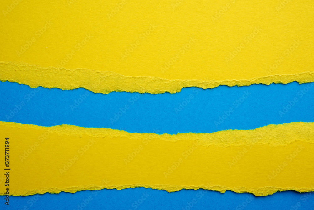 Obraz premium abstract background with torn edges of yellow paper, blue backdrop