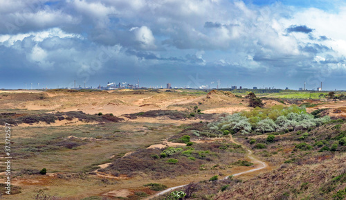 Dune landscape with blast furnaces of a steel plant on the horizon