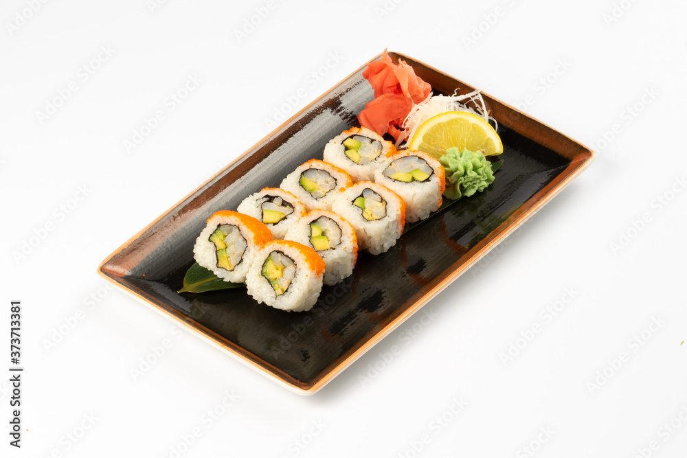 A portion of maki sushi with an assortment of Japanese side dishes in a rectangular ceramic plate on a white plate. A portion of maki sushi with an assortment of Japanese side dishes in a rectangular ceramic plate on a white plate.