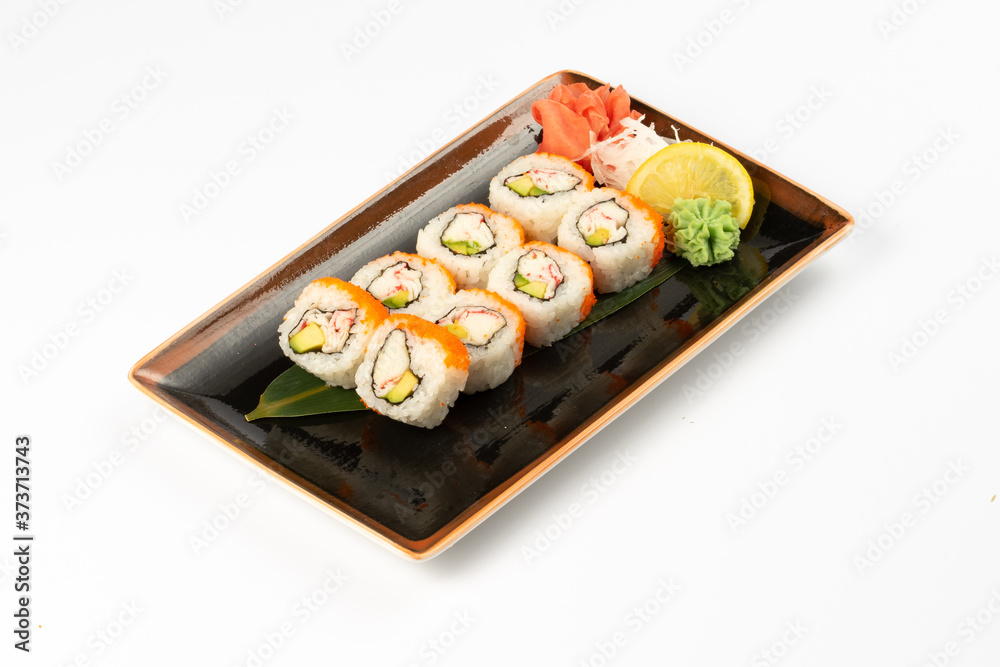 A portion of maki sushi with an assortment of Japanese side dishes in a rectangular ceramic plate on a white plate. A portion of maki sushi with an assortment of Japanese side dishes in a rectangular ceramic plate on a white plate.
