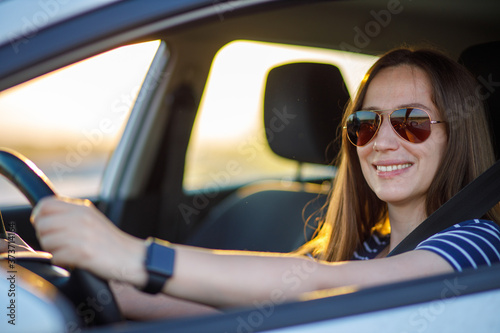 Young woman in sunglasses steering car at sunset © skumer