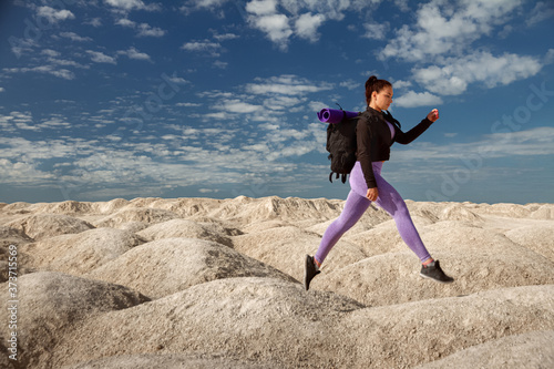 young woman one tourist running, rear view on hill area in sportswear and with backpack side view, concept of healthy lifestyle, sports, overcoming obstacles © ksenija1803z