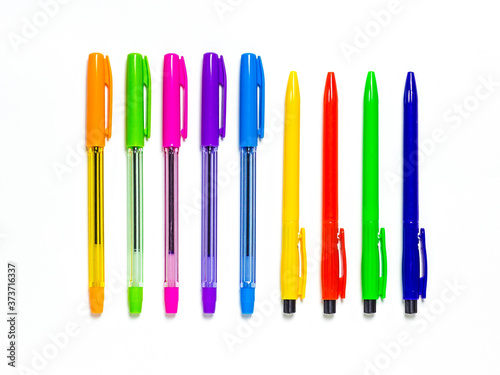 Multicolored pens lie exactly in a row on a white background. Stationery and school supplies