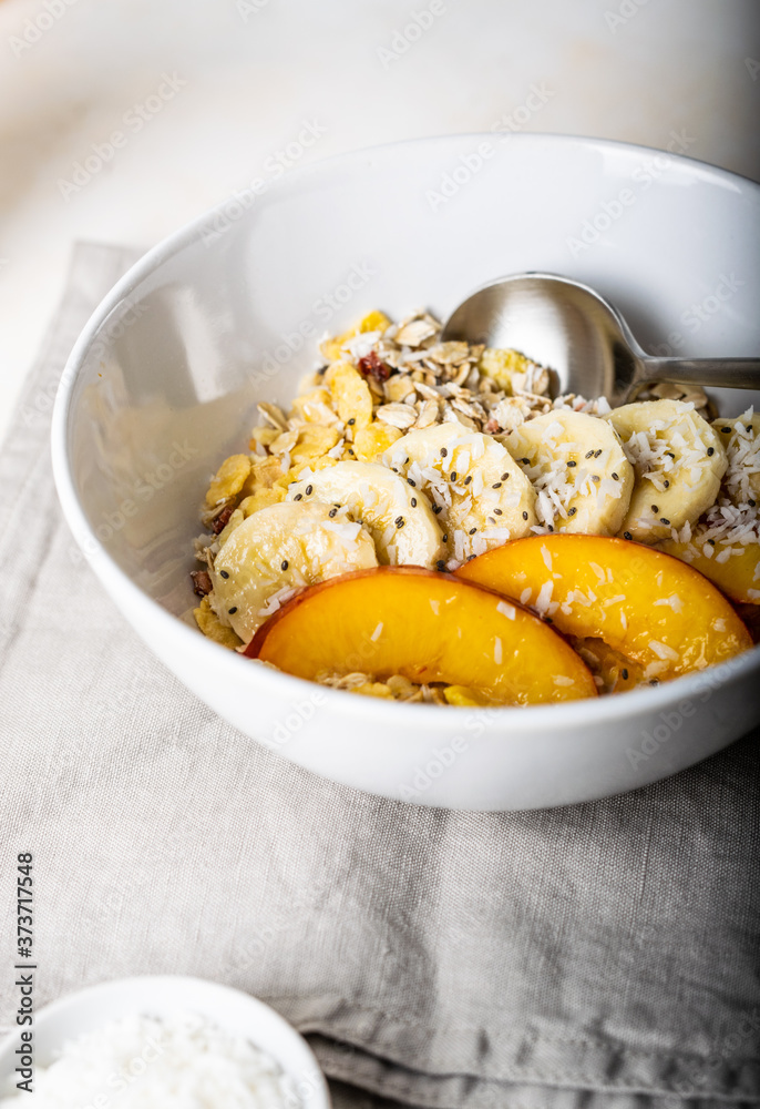 Granola with fruits for breakfast in a deep white plate close-up