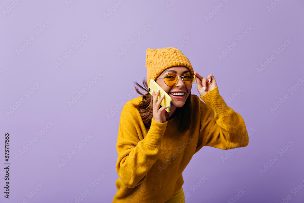 Cheerful 21 year old girl with auburn hair has funny, interesting conversation by phone. Laughing woman looking through yellow sunglasses with interest posing for portrait Cheerful 21 year old girl with auburn hair has funny, interesting conversation by phone. Laughing woman looking through yellow sunglasses with interest posing for portrait