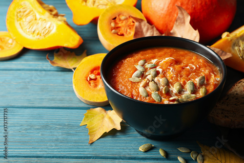 Composition with pumpkin soup with seeds on wooden background, space for text