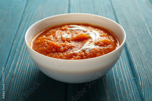 Bowl of pumpkin puree on wooden background, close up