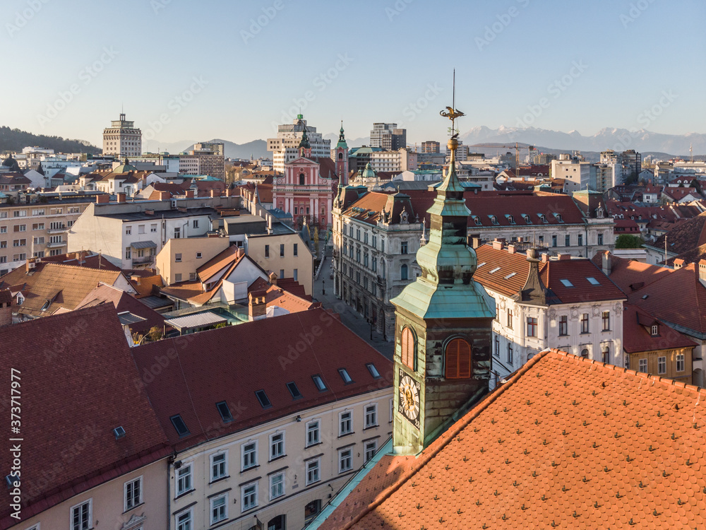 Scenic panoramic aerial drone view of rooftops of medieval city center, town hall and cathedral church in Ljubljana, capital of Slovenia, at sunset.