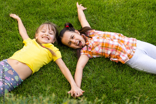 Portrait of two little girls sisters fighting on home backyard. Friends girls having fun. Lifestyle candid family moment of siblings quarreling playing together. photo