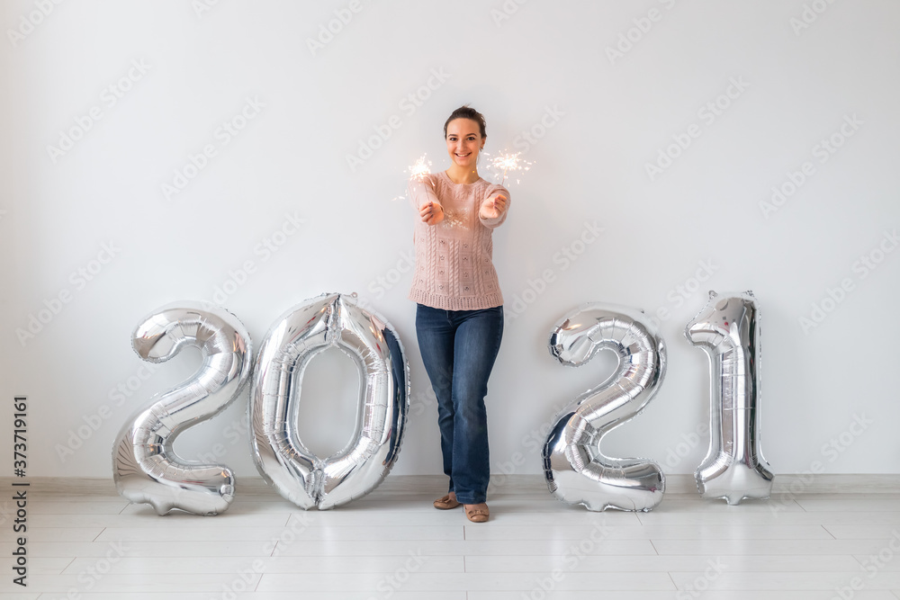 New Year celebration and party concept - Happy young woman with sparklers near silver 2021 balloons on white background. New Year celebration and party concept - Happy young woman with sparklers near silver 2021 balloons on white background.