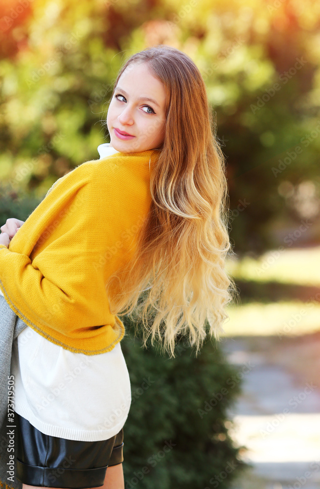 А young girl with luxurious wavy blond hair in a reversible yellow and gray scarf, white turtleneck, black short leather shorts. Autumn clothes for girls. Fashion and beauty. Autumn concept. А young girl with luxurious wavy blond hair in a reversible yellow and gray scarf, white turtleneck, black short leather shorts. Autumn clothes for girls. Fashion and beauty. Autumn concept.