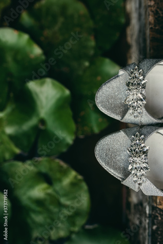 Top view bridal details. Wedding shoes heels with waterlilies background. Decoration, fashion, elegance, womanly concept.
