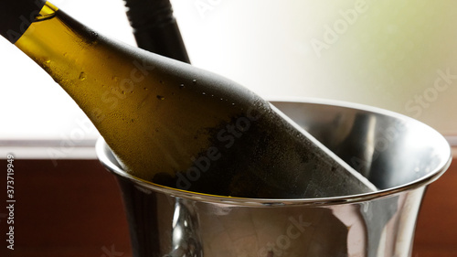 Bottle of bubbly wine resting in metal ice bucket
