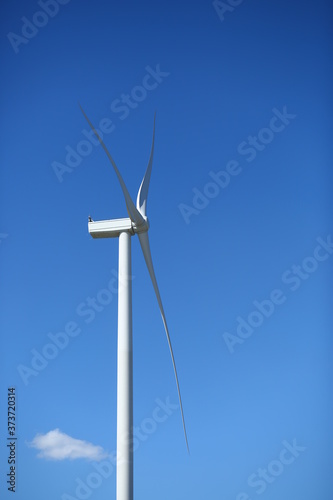 Profile view of wind power energy generator against blue sky