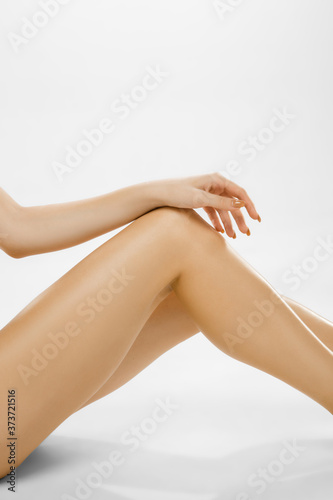 Beautiful female legs with hand isolated on white background. Beauty, cosmetics, spa, depilation, treatment and fitness concept. Fit and sportive, sensual body with well-kept skin in underwear.