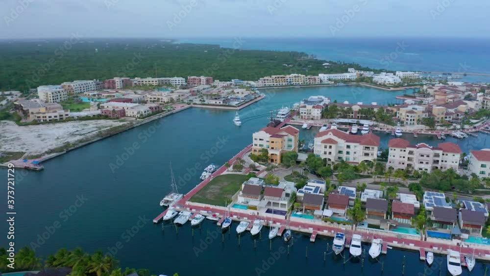 Scenic shot of cap cana marina, beautiful blue water buildings, white yacht making its entrance Scenic shot of cap cana marina, beautiful blue water buildings, white yacht making its entrance