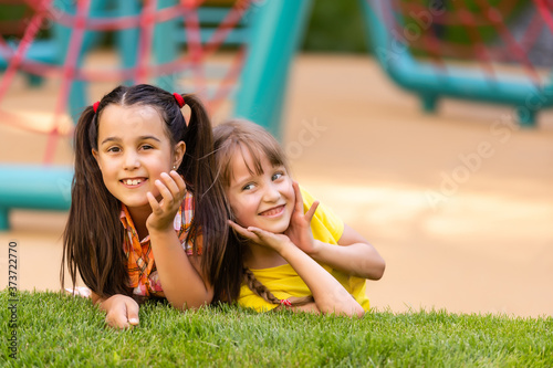 Portrait of two little girls sisters fighting on home backyard. Friends girls having fun. Lifestyle candid family moment of siblings quarreling playing together. photo