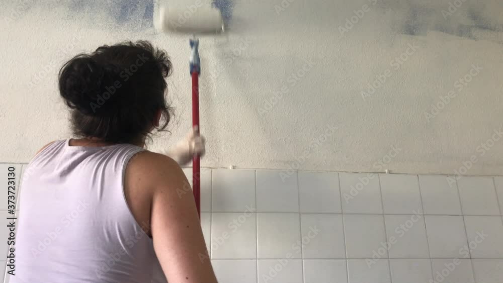 Mujer pintando la pared de su casa