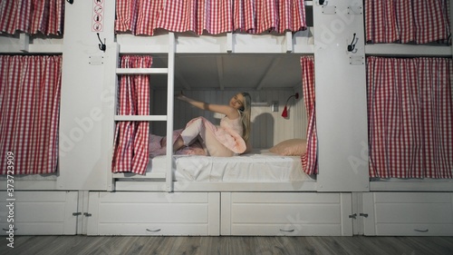 Young attractive woman stretches in bed in the hostel room