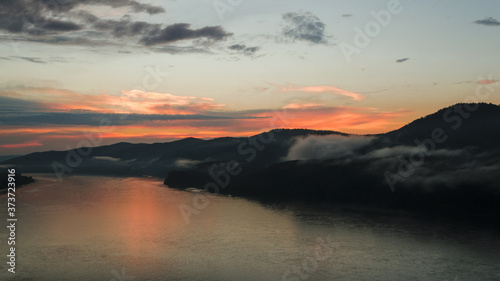 sunset from a bird's eye view on the background of mountains with clouds and a large river sunset landscape