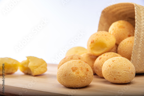 Cheese bread  P  o de queijo  Brasil   falling from a basket onto a cutting board and checkered tablecloth  selective focus.