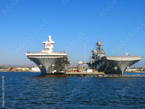 Two aircraft carriers parked next to each other and being repaired and readied in San Diego bay where the US navy naval base is located.
