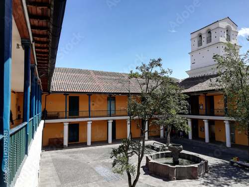 Inner courtyard, fountain and bell tower of the Museum of the City in Quito, Ecuador, seen from the upper floor during a sunny day

