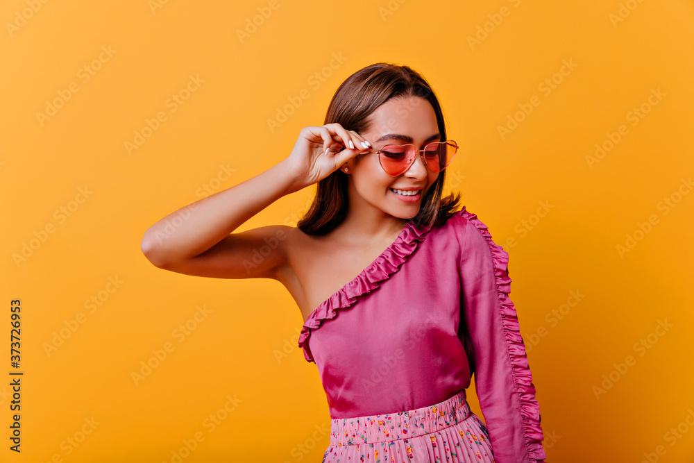 fragile, shy woman of 21 years old in blouse with bare shoulder smiles in friendly way, looking down. closeup portrait of stylish model on isolated background fragile, shy woman of 21 years old in blouse with bare shoulder smiles in friendly way, looking down. closeup portrait of stylish model on isolated background