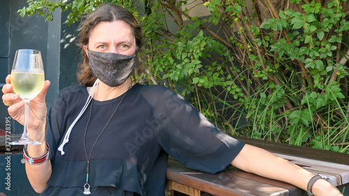 Female Tourist with fce mask drinking wine in restuarant. photo