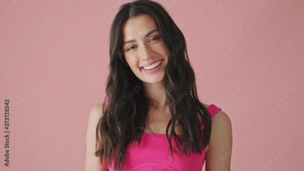 An attractive young woman is laughing standing isolated over pink background An attractive young woman is laughing standing isolated over pink background