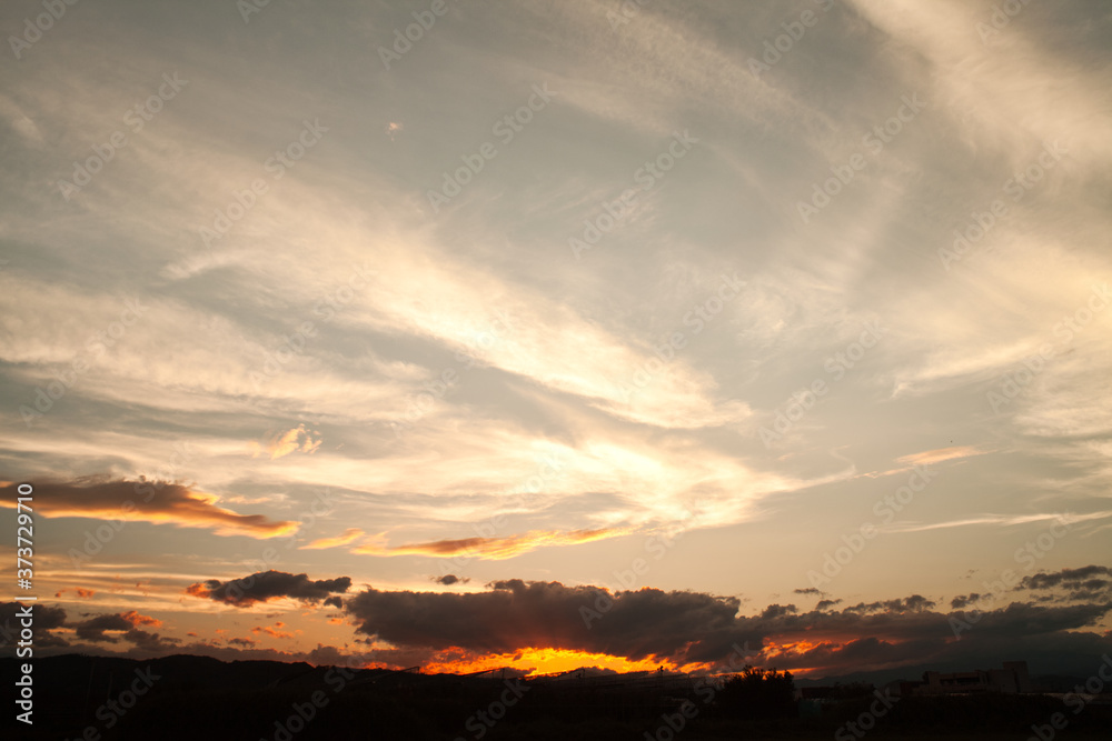 Naklejka premium 燃えるような夕日と流れる雲