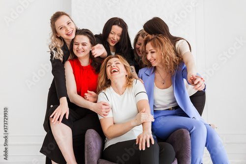 Seven diverse colleagues, co-workers stand ans seat together in office, hug each other.