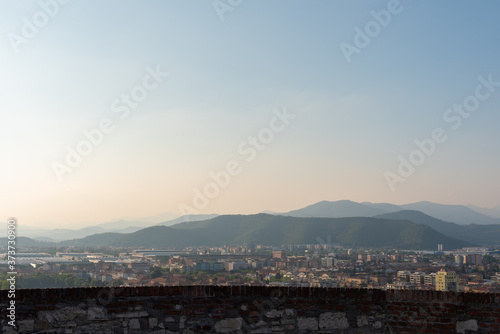 Aerial panoramic sunset view of residential district with buildings of Brescia city and Alps mountain range, blue cloudy sky background, Lombardy, Italy. Brescia Castle. © OlgaLitvinovaFoto