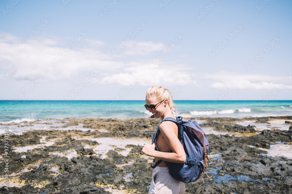 Cheerful woman with backpack standing on beach