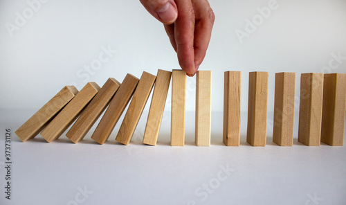 Businessman placing his hand to stop falling dominos. Beautiful white background. Copy space. Business concept.