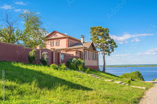 Old wooden house with carved windows on hill by river