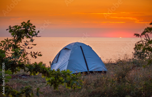 Namiot na tle wschodzącego słońca na plaży morza Bałtyckiego 