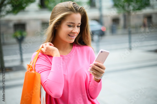 Young woman using her smartphone while shopping in a city