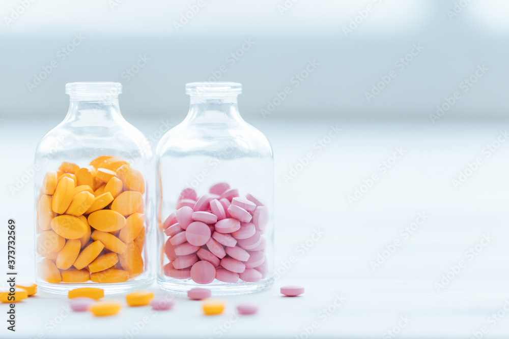 Assorted pharmaceutical medicine pills in glass bottle on wooden table background. Pharmaceutical medicament. Dietary supplements, drugs, Pharmacy, Medicine and healthcare concept. Assorted pharmaceutical medicine pills in glass bottle on wooden table background. Pharmaceutical medicament. Dietary supplements, drugs, Pharmacy, Medicine and healthcare concept.