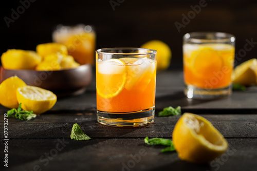 Lemon iced tea drink photo on dark background. A refreshing summer drink made of fresh hand squeezed lemon mixed with cold black tea, ice and sugar. Add orange juice & alcohol for a cool cocktail.
