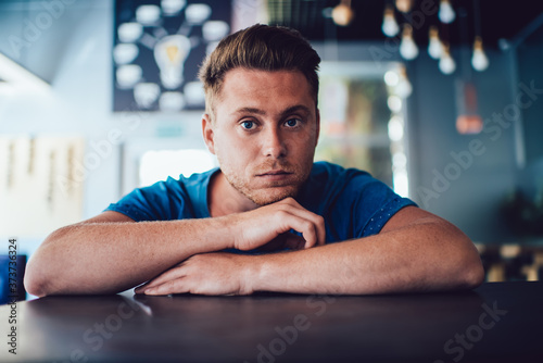 Pensive guy leaning on hands at table in cafe © BullRun