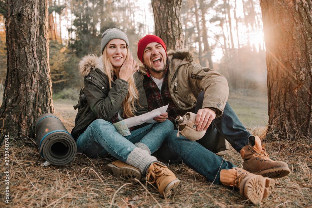 Travel couple camping with map having fun in the forest. Concept of trekking, adventure and seasonal vacation. Travel couple camping with map having fun in the forest. Concept of trekking, adventure and seasonal vacation.