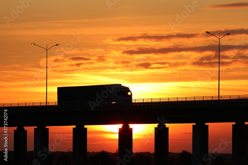 A truck driving on a flyover at sunset
