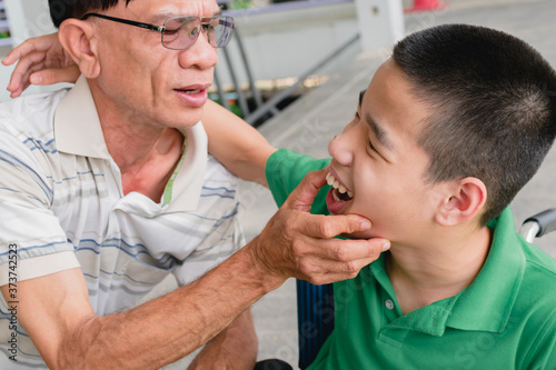 The father examined the disabled child on the wheelchair oral hygiene and dental  Lifestyle in the education age of special children  The handsome boy is happiness face  Happy disability kid concept.