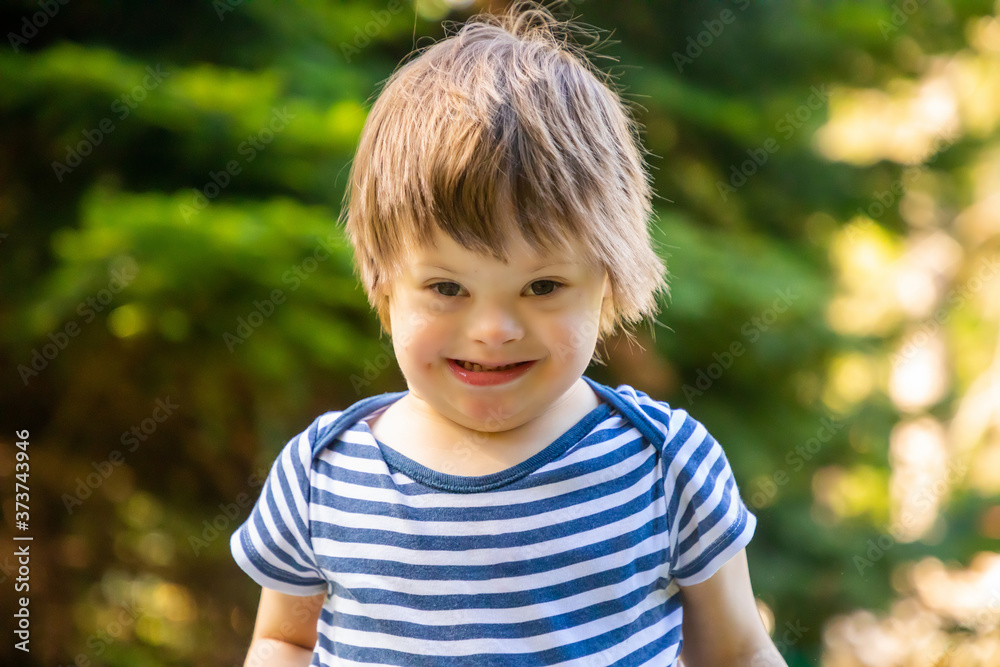 Portrait of baby boy with Down syndrome playing in summer day on nature Portrait of baby boy with Down syndrome playing in summer day on nature