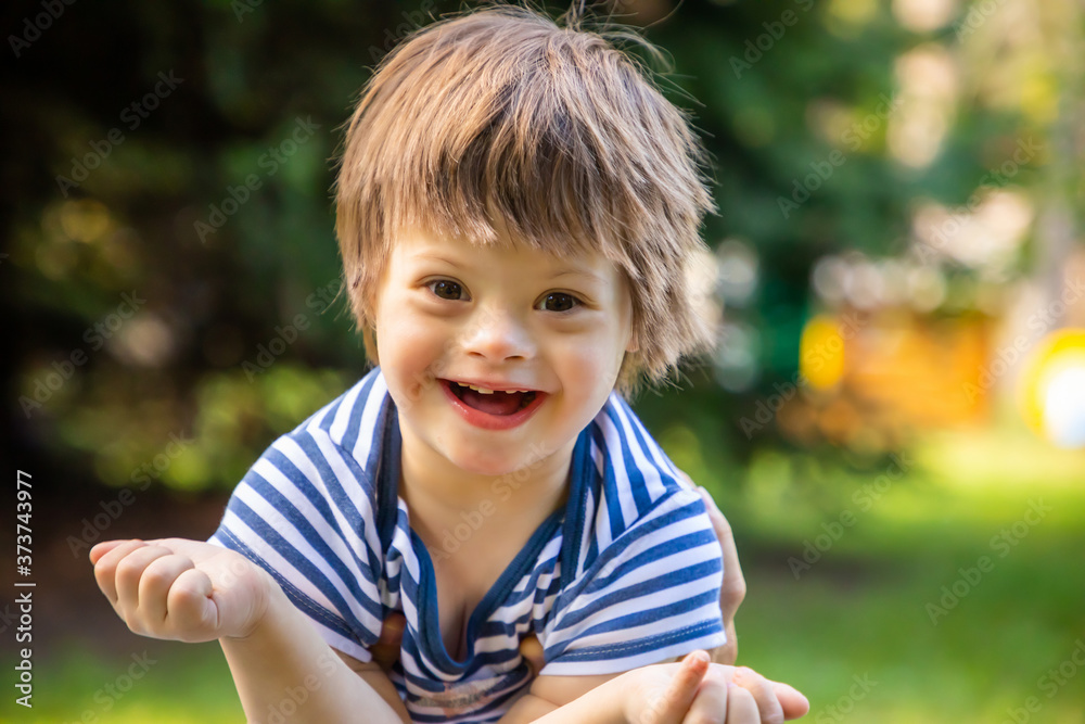 Portrait of baby boy with Down syndrome playing in summer day on nature Portrait of baby boy with Down syndrome playing in summer day on nature